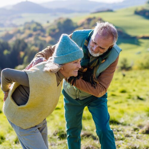 Senior woman with having pain in back during autumn walk, her husband taking care of her.